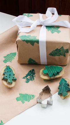 a present wrapped in brown paper next to cookie cutters and christmas tree cutouts