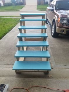 three blue benches sitting on the side of a road next to a truck and grass