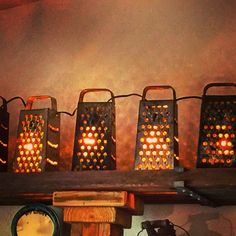 four lit up lanterns sitting on top of a shelf