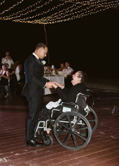 a man in a wheel chair shaking hands with another person on the dancefloor