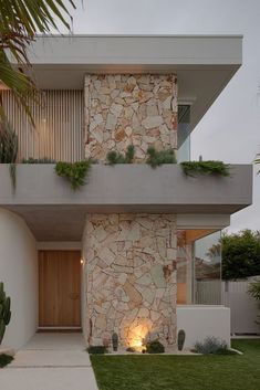 a modern house with stone facade and plants on the balconies