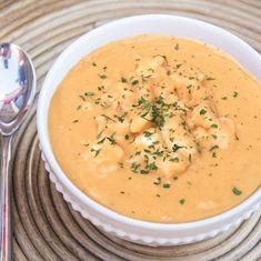 a white bowl filled with soup on top of a table next to a silver spoon