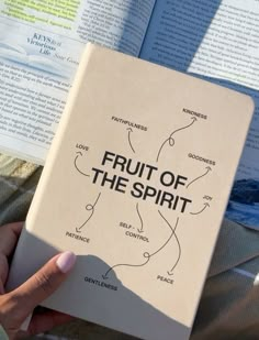 a person holding up a book with the words fruit of the spirit written on it