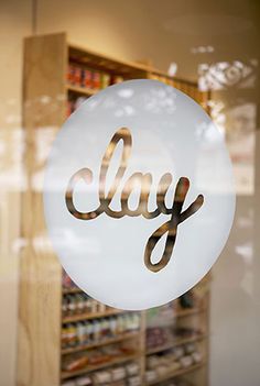 a glass sign that says clay on it in front of a store window with shelves