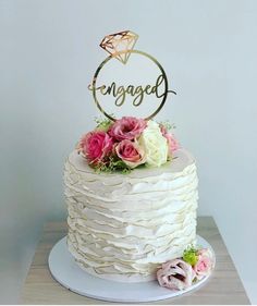 a white cake with pink flowers and an engaged sign on top