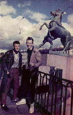 two men standing in front of a horse statue