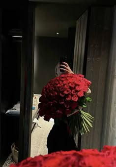 a woman taking a selfie in front of a mirror holding a bouquet of flowers