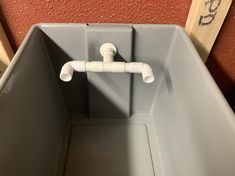 a gray plastic container with two white pipes attached to it