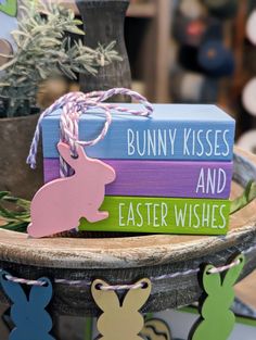 some bunny kisses and easter wishes are sitting on a wooden tray next to a potted plant