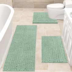 three bathroom rugs on the floor in front of a bathtub and toilet,