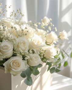 a bouquet of white roses and greenery in a vase