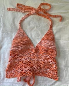 an orange crocheted halter top on a white sheet with a knot at the neck