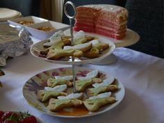 three tiered trays with cakes and desserts on them sitting on a table