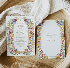 the wedding stationery is laid out on top of a wooden bowl with white linen