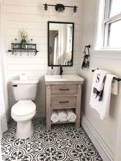 a white toilet sitting next to a sink in a bathroom under a mirror and towel rack