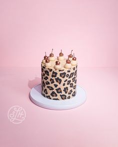 a leopard print birthday cake on a blue plate against a pink background with the word monogram