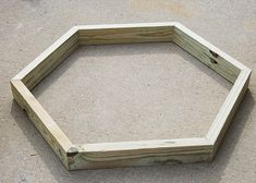 a hexagonal wooden frame sitting on the ground with sand in front of it