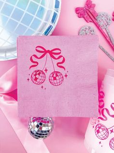 a pink napkin with two disco balls on it next to other party accessories and decorations