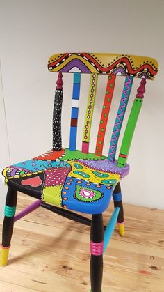 a colorful wooden chair sitting on top of a hard wood floor