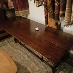 a wooden table with an apple on it in front of some rugs and curtains