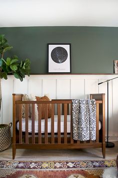 a baby crib in the corner of a room with green walls and rugs