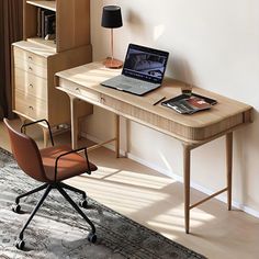 a laptop computer sitting on top of a wooden desk next to a lamp and chair