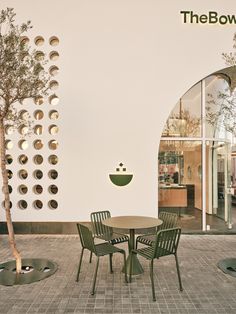 an outdoor table and chairs in front of a white wall with the bow logo on it