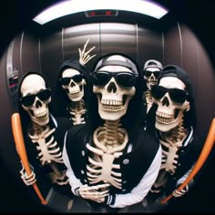 four skeletons dressed in black and white with sunglasses