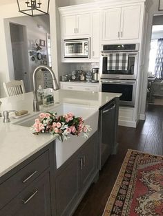 a white kitchen with gray cabinets and an area rug on the floor in front of the sink