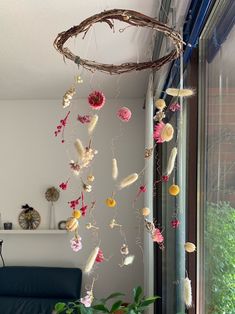 a room with a blue couch and some flowers hanging from the ceiling next to a window