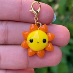 a yellow and orange sun charm sitting on top of a persons hand with it's eyes closed