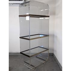 a glass and metal shelf with three shelves on each side, against a white wall