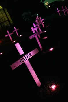 three crosses lit up in the dark at night with candles around them and one sign that says byes