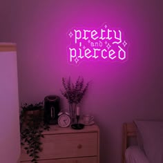 there is a neon sign that says pretty and pierced on the wall next to a dresser