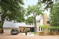 a truck is parked in front of a house with a stone wall and tree lined driveway