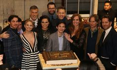 a group of people standing next to each other with a cake in front of them