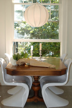 a dining room table with white chairs and a lantern hanging from the ceiling over it