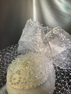 Made from scratch using white silk, sheer floral ribbon and pearls.   Pair this with a white suit or white sheath to be an elegant vintage bride.   I learned to make hats in college but really fell in love with making hats when I created a hat for my son's wedding.   Designing these hats incorporates a lifetime of playing with textures and colors.   Free Hat box with Free Shipping! International Customs Charges NOT included. Making Hats, Bridal Fascinator, Pearl Gifts, Winter Bride, White Suit, Wedding Fascinators, Dupioni Silk, Floral Ribbon, Personalized Gift Tags