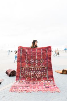 a woman is holding up a rug on the ground