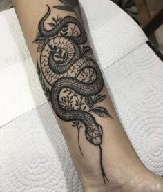 a black and white tattoo on the arm of a woman with a snake in it