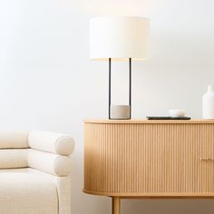 a living room with a couch, table and lamp on top of the sideboard