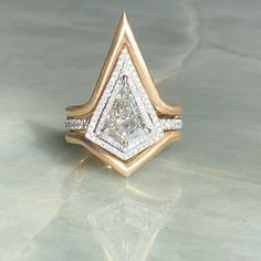 a gold and white diamond ring sitting on top of a table