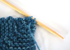 a blue knitted object with a wooden knitting needle