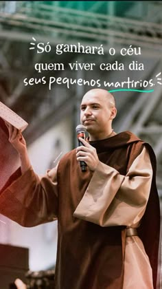 a man holding a microphone in his right hand while standing next to a statue with words written on it