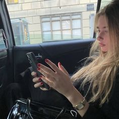 a woman sitting in the back seat of a car looking at her cell phone