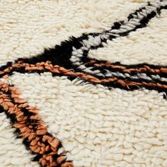 an area rug with different colored lines on the ground and black, white, orange, and grey colors