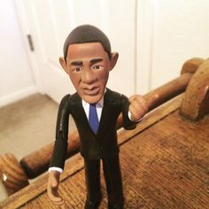 a toy man in a suit and tie standing on a wooden floor next to a door