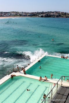 people are swimming in an outdoor pool next to the ocean