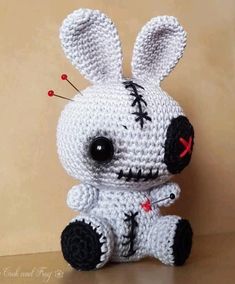 a white crocheted stuffed animal sitting on top of a wooden table next to a brown wall