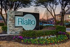 the sign for ri alto at dusk with cars parked in the parking lot behind it